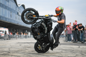 Das Bild zeigt einen Stuntfahrer mit seinem Motorrad bei den Hamburg Harley Days. Im Hintergrund sind Absperrungen und Besuchende zu sehen.