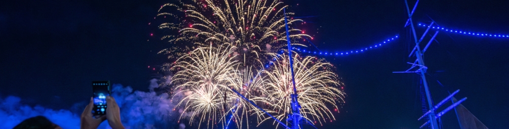 Der Zuschnitt zeigt ein Feuerwerk der Hamburg Cruise Days sowie ein in die Luft gestrecktes Handy, um dieses zu fotografieren.