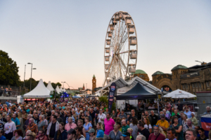 Das Bild zeigt ein Riesenrad und viele Menschen auf dem Landungsbrückenvorplatz während der Cruise Days 2023.